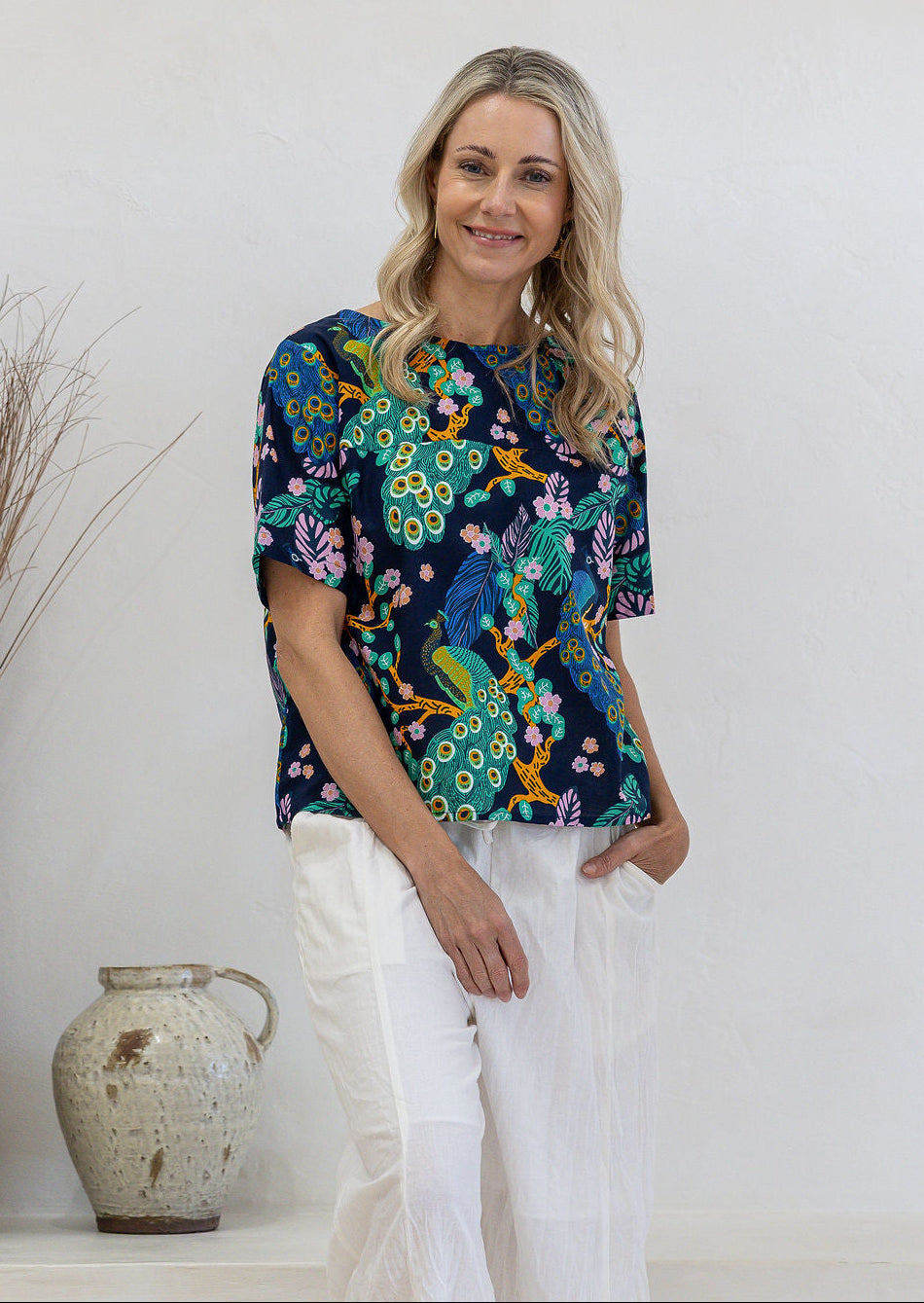 Woman wearing a navy based floral print relaxed fit cotton top with short sleeves and high neckline