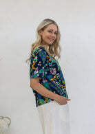Woman standing side on wearing cotton short sleeved relaxed fit top