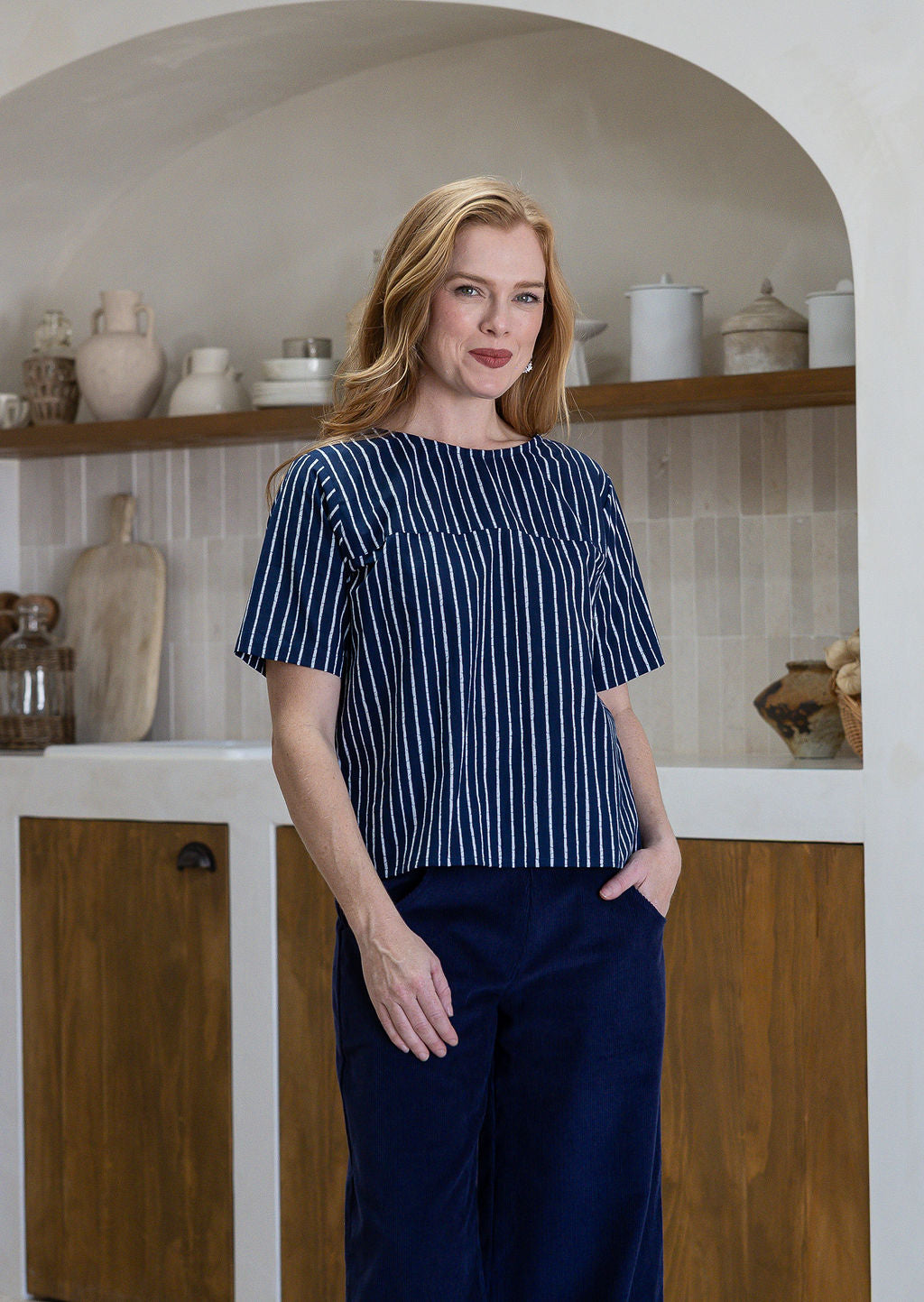 Woman wearing a navy striped cotton loose fit short sleeved top and pants with hand in pocket