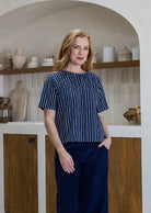 Woman wearing a navy striped cotton loose fit short sleeved top and pants with hand in pocket