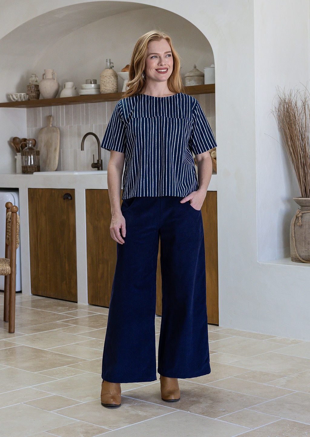 Woman wearing a navy blue and white  striped short sleeved cotton top and navy pants.