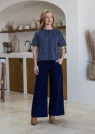Woman wearing a navy blue and white  striped short sleeved cotton top and navy pants.