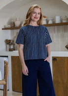 Woman wearing a navy striped relaxed fit cotton top with short sleeves and high neckline