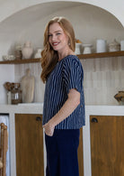 Woman standing side on wearing cotton short sleeved relaxed fit top