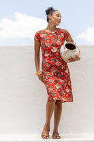 Woman in bright red floral cotton dress on wall holding pot