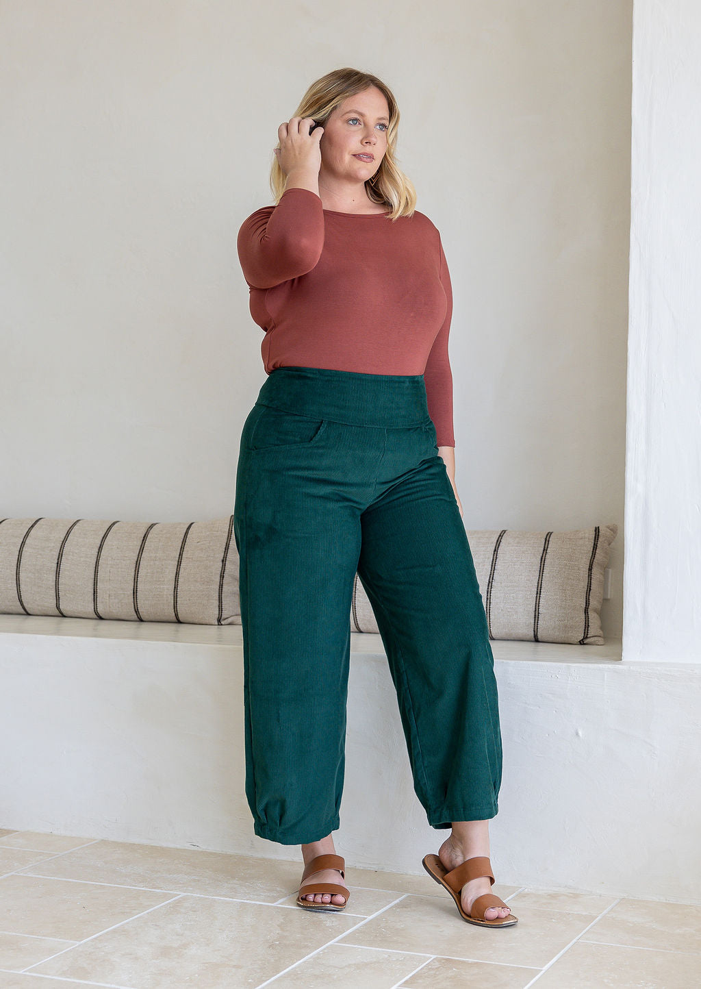Model wears corduroy wide leg pants with side zipper, pockets and small pleats at ankles.