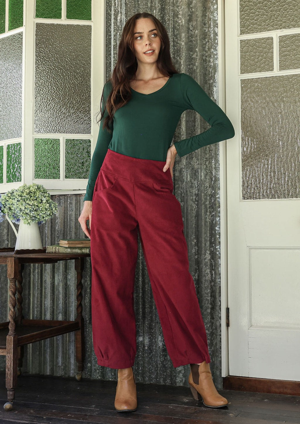 Model wearing a cotton corduroy wide leg pants in red paired with a basic top in green