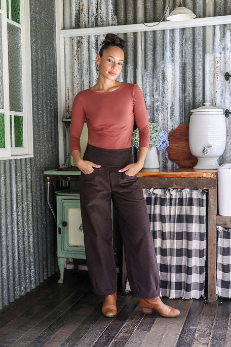 Woman wearing a corduroy dark brown pants with hands in pockets