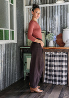 Woman standing sideways wearing a cotton corduroy wide-leg dark brown pants paired with a basic rayon top