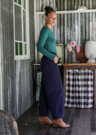 Model standing sideways wears corduroy wide leg pants with side zipper, pockets and small pleats at ankles.