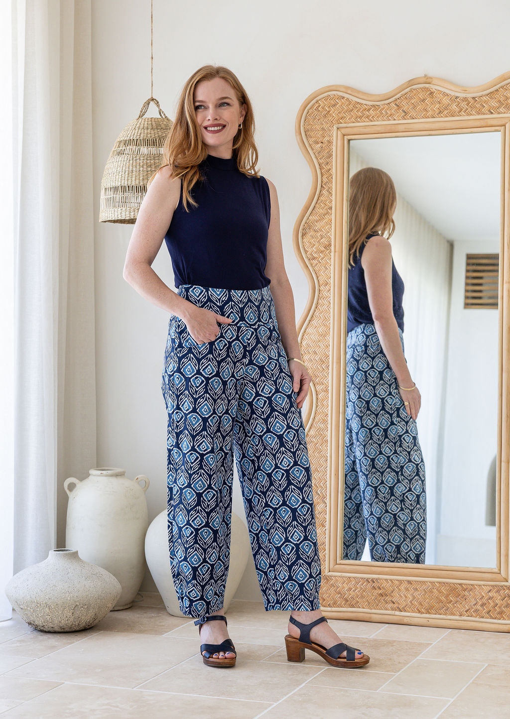Woman wearing cotton wide leg pants in black based floral print with one hand in pocket paired with basic navy top 