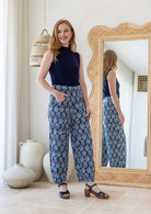 Woman wearing cotton wide leg pants in black based floral print with one hand in pocket paired with basic navy top 