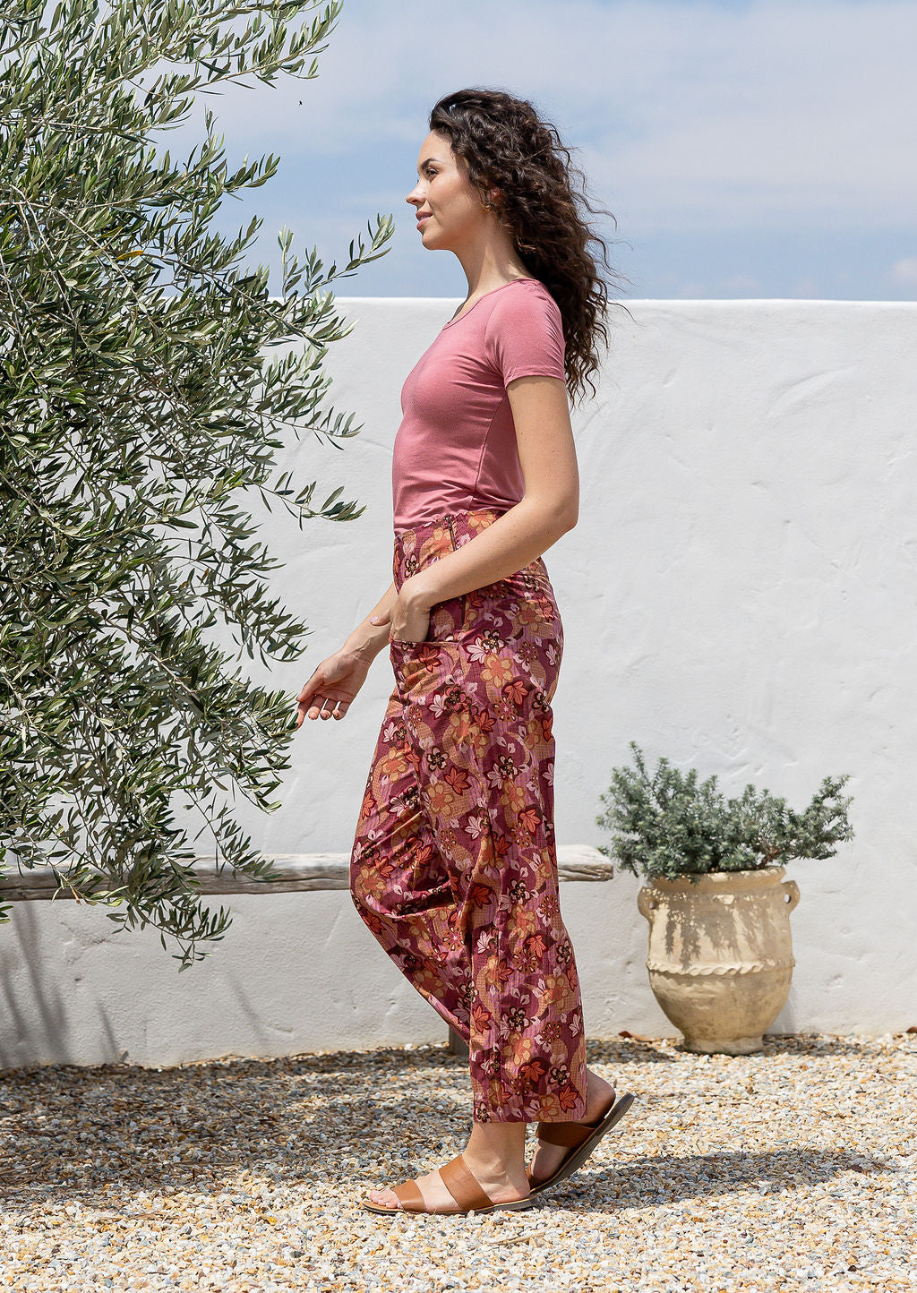 Woman stands sideways wearing a high waisted, wide leg cotton pants with side zipper and pockets.