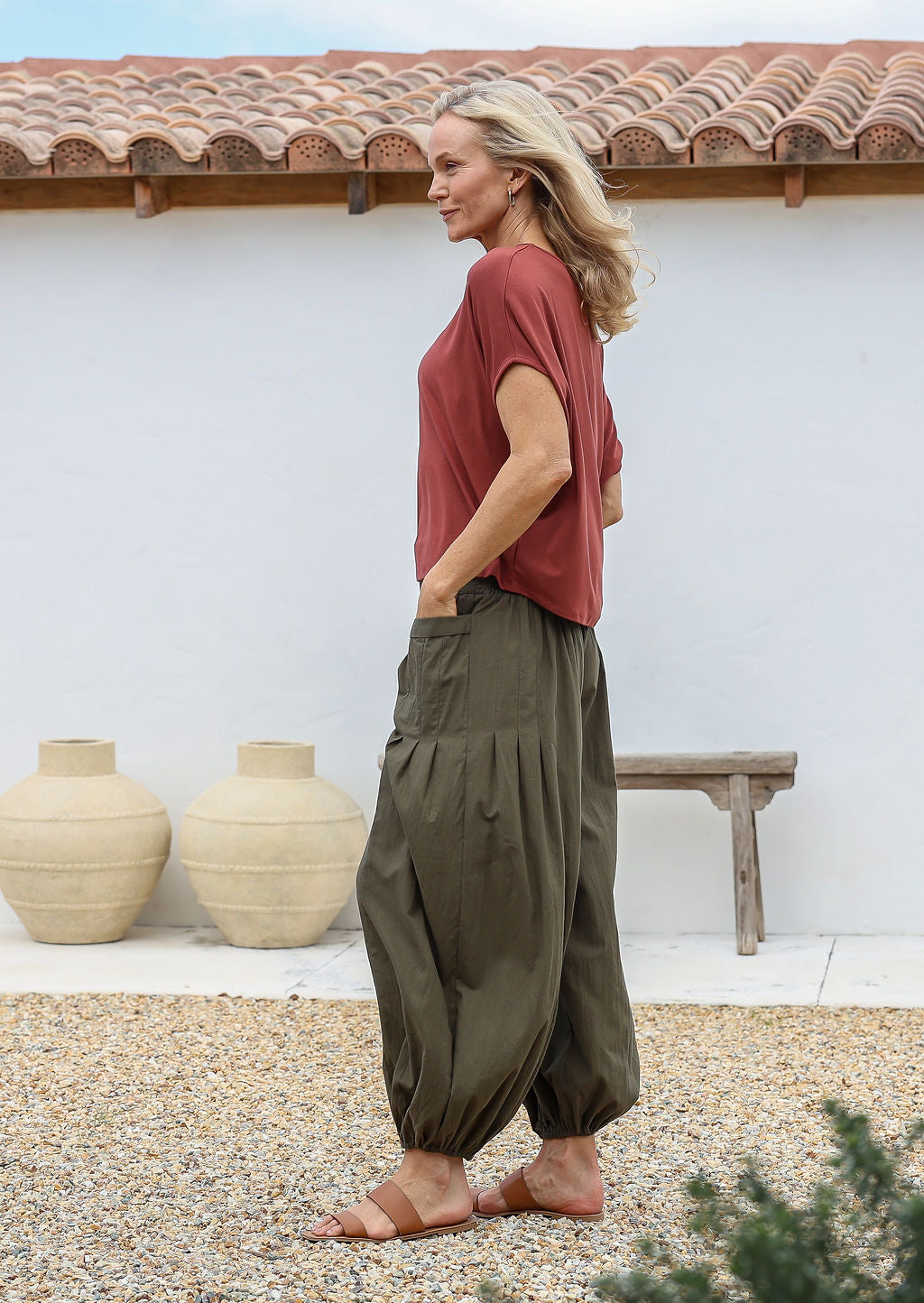 Woman wearing a basic rayon top and green harem style pants with elasticated ankles, waist and hands in pockets.