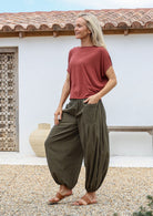 Woman wears terracotta rayon top with aladdin style cotton harem pants featuring deep pockets and elasticated ankles and waist.