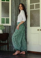 model stands sideways wearing a floral cotton pants with elastic ankles and waist.