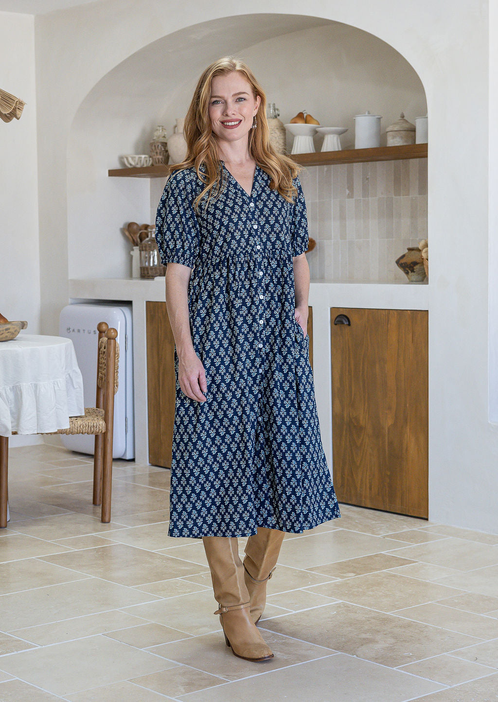woman wearing a 100% cotton dress in navy blue based floral print with one hand in pocket