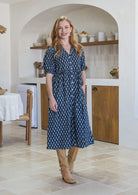 woman wearing a 100% cotton dress in navy blue based floral print with one hand in pocket