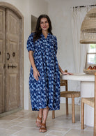 Woman wearing navy based colourful floral cotton button through dress with side pockets