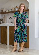 Woman wearing a navy based colourful floral cotton button through dress with one hand in hidden side pocket