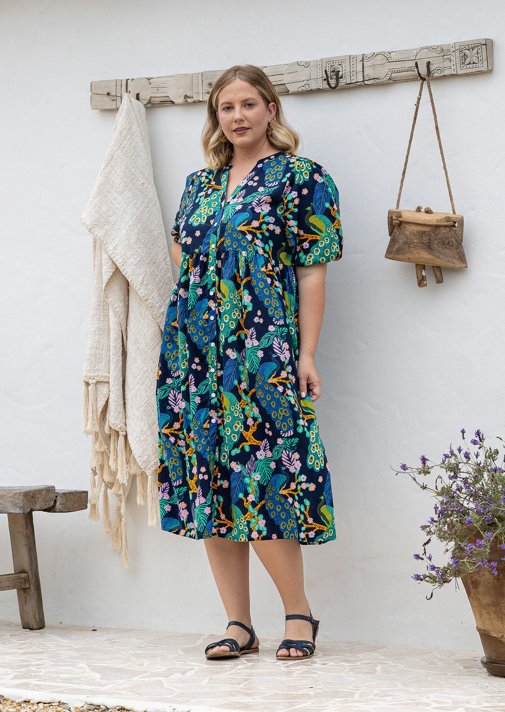 Woman in a floral dress standing against a white wall