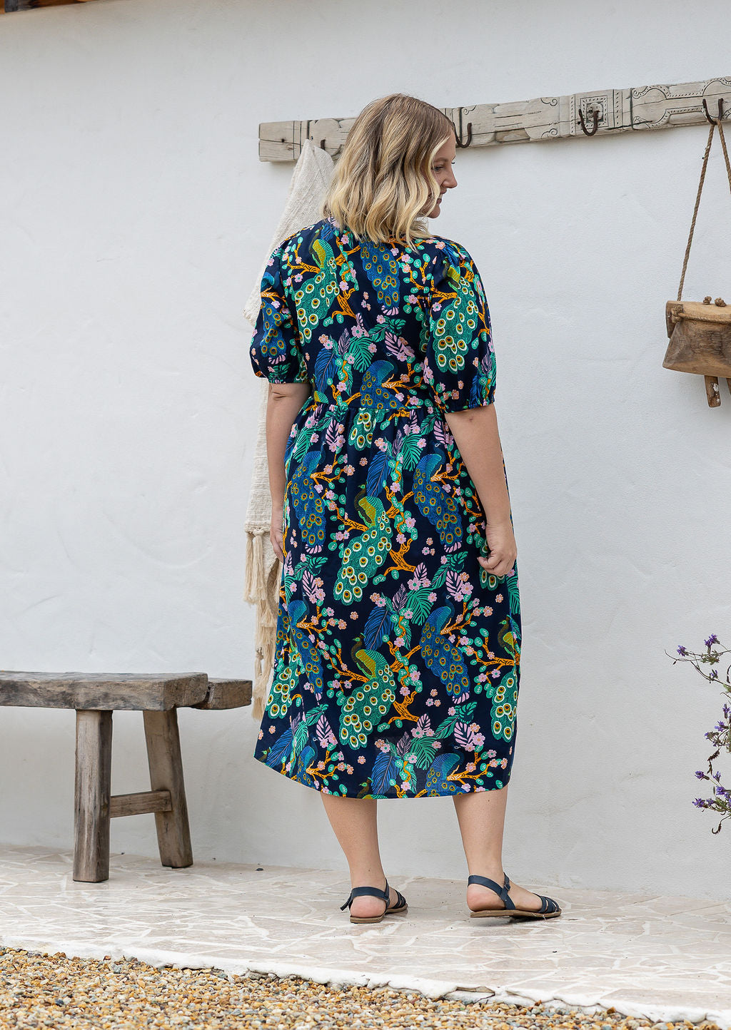 Woman standing backwards on in a navy floral cotton midi length dress standing outdoors