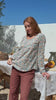 Video of a model wearing 100% cotton long sleeve top with round neckline and tiny pleat detail from the center of the neckline.