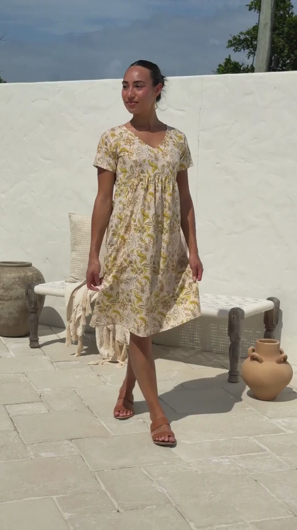 Video of a woman wearing a 100% cotton Etta Dress in Primrose, yellow floral print, V-neck short-sleeve midi dress. 