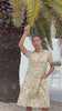 Video of a woman wearing a cream based cotton floral short sleeve dress with round neckline