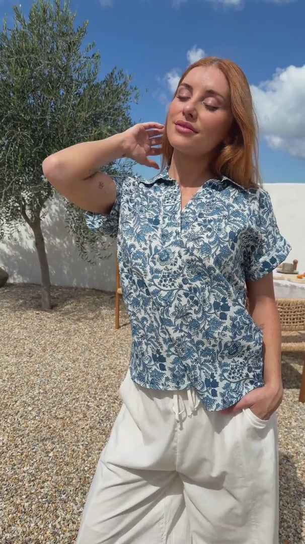 Video of woman poses in relaxed fit cotton short sleeve top with rolled cuffs sleeves, collar and V neckline.