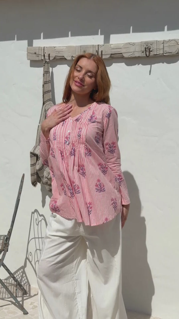 Video of a woman wearing a 100% cotton Pink striped floral long-sleeve blouse with pleated front. 