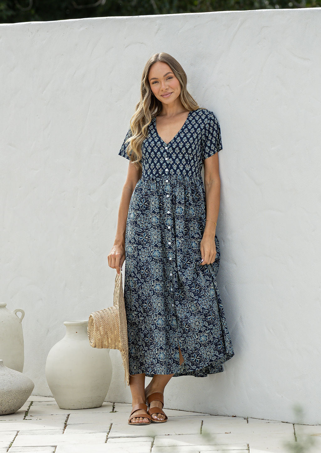 Woman posing in a relaxed fit, short sleeved, floral cotton dress with V- neckline, drawstring waist tie and pockets 