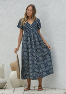 Woman wearing a relaxed fit, button through cotton dress in navy blue base floral print with V neckline.