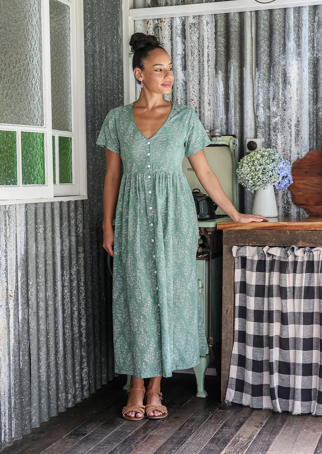 Woman posing in a relaxed fit, short sleeved, floral cotton dress with V- neckline, drawstring waist tie and pockets 