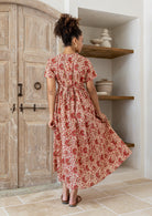 Woman stands backwards wearing a 100% cotton dress with short sleeves, pockets, and a drawstring tie at the back.