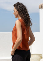 Woman wears cotton top with small gathers under the neckline yoke, both front and back, that gives this top a loose fit