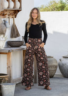 Model poses in floral cotton pants with side zipper, hands in pockets and wide leg fit