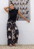 Model wears black based floral print wide leg cotton pants with pockets and side zip 