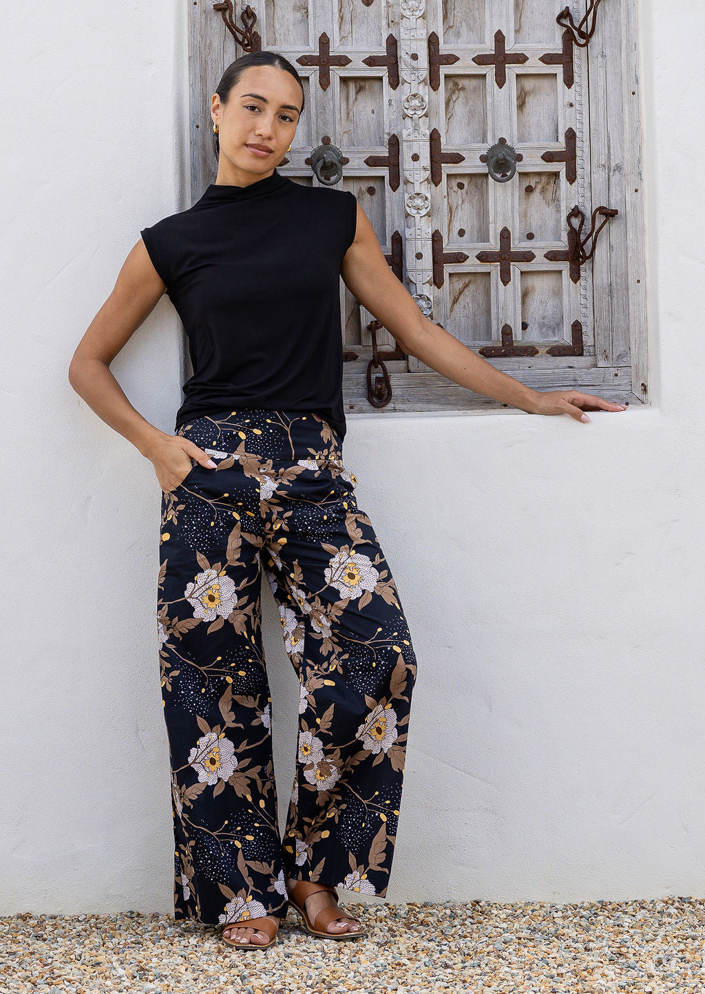 Model standing wears 100% cotton wide leg pants in black based floral print