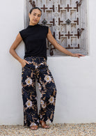 Model standing wears 100% cotton wide leg pants in black based floral print