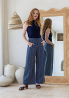 Model wearing a wide leg 100% cotton pant with navy based white striped print standing against a mirror