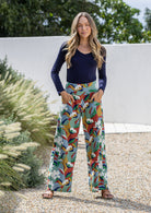 Model wears floral print wide leg cotton pants with hands in pockets and side zip