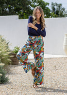 Woman wearing colorful patterned pants and a navy top outdoors.
