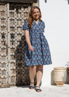 Woman wearing a knee length relaxed fit button through 100% cotton dress with elbow length sleeves