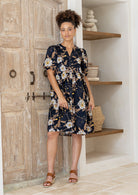Woman wearing a knee length relaxed fit button through 100% cotton dress with elbow length sleeves