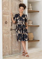 Woman with one hand in pocket wearing a 100% cotton dress with black based floral print