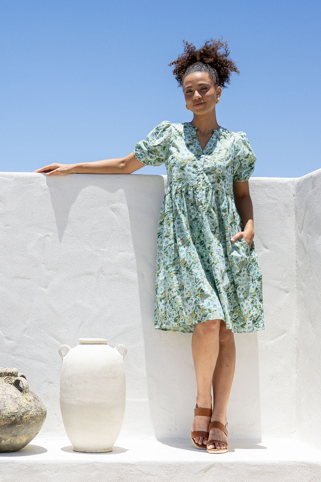 Woman with one hand in pocket wearing a 100% cotton dress with sage green based floral print