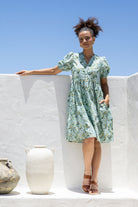 Woman with one hand in pocket wearing a 100% cotton dress with sage green based floral print