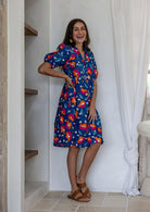 Woman standing wearing a 100% cotton dress with royal blue based floral print