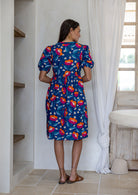 Woman standing backwards wearing a 100% cotton short sleeve dress in royal blue based floral print